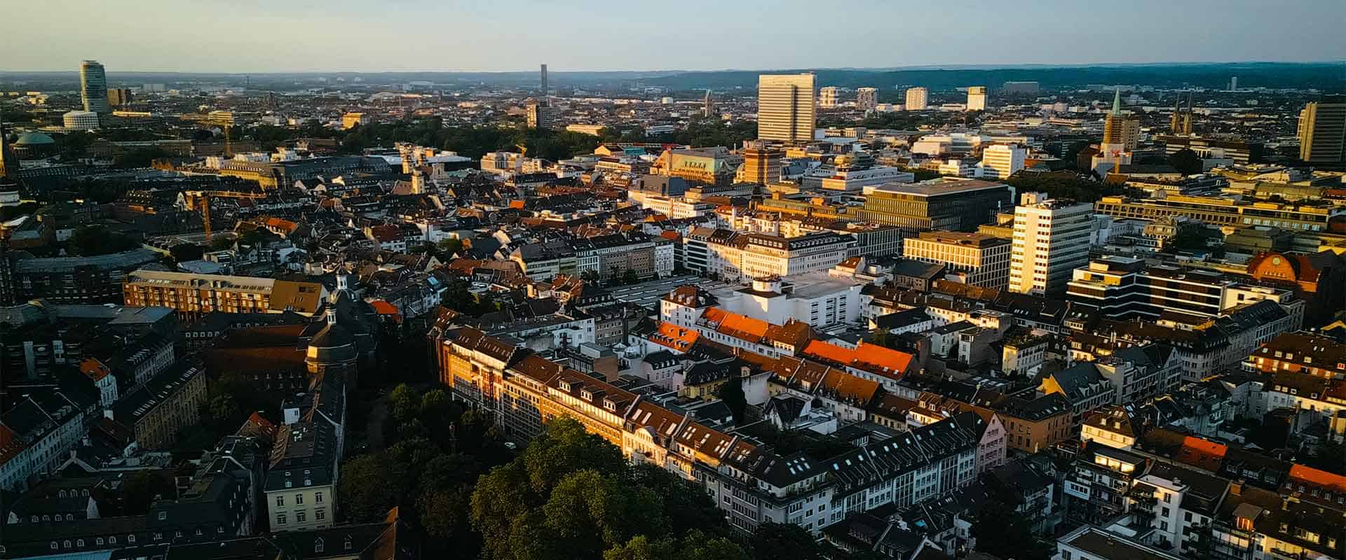 Panoramaaufnahme einer Stadt bei Sonnenuntergang, zeigt moderne und historische Gebäude, ideal für Escort Service Website, um die urbane Atmosphäre zu präsentieren.