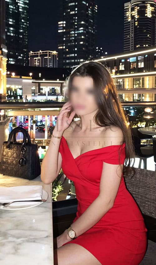 Attractive escort lady in a red dress at night in the city.