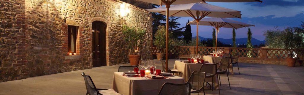 A covered terrace bathed in evening light with elegantly set tables and a view of the sunset, ideal for exclusive companion and escort service experiences in a romantic atmosphere.
