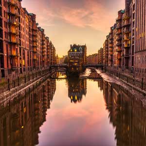 Majestic old town at sunset in Hamburg, with historic buildings on the water and a reflecting sky, ideal for exclusive escort service experiences in Germany.