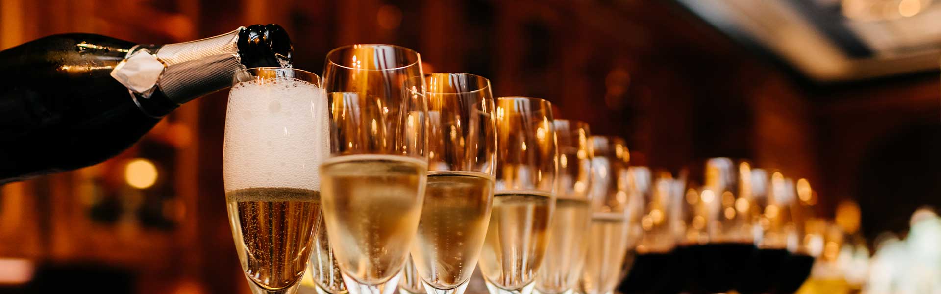 Several champagne glasses filled with sparkling wine on a bar counter at an elegant event, stylish and festive.
